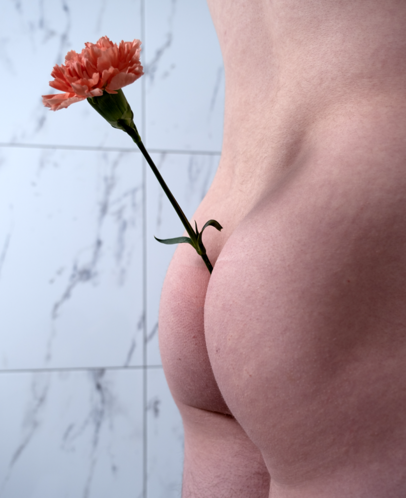 An orange flower emerges out of a butt crack in front of a marble wall
