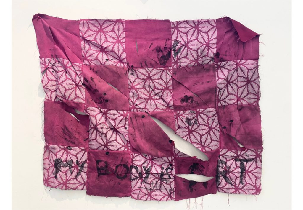 An image of a quilt that has been torn and ripped up. The words "my body is art" is thrown across the bottom
