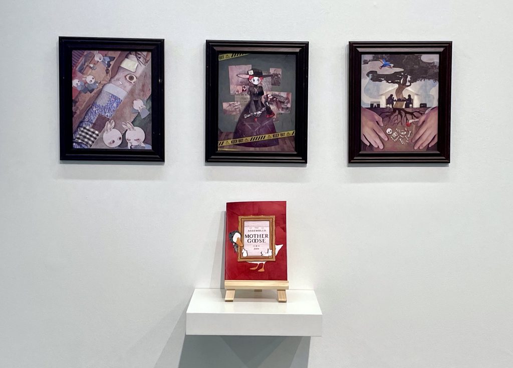 Photo of the three framed pieces hanging on the wall with the book displayed in front at the show.