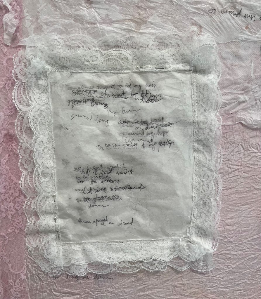 A detail image of "bedroom", featuring a pillow made from lace and parchment, with a poem written on it.