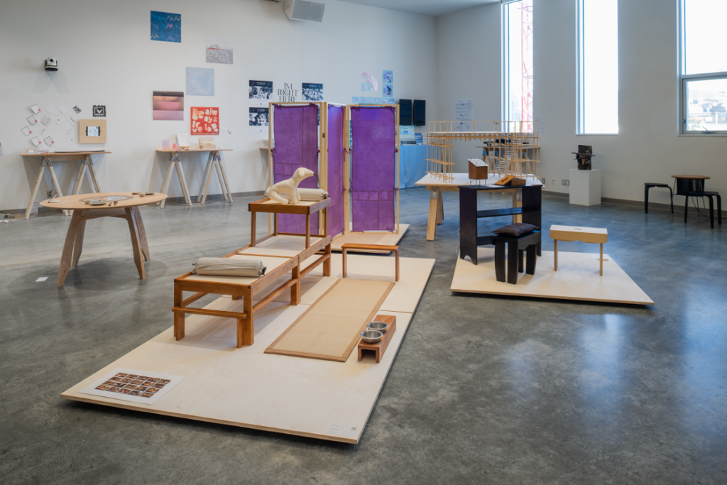 Installation view of a number of free-standing industrial design and wall-mounted pieces. The free standing pieces are predominantly made of wood and one with wood and fabric, and take on the forms of various furniture pieces. 